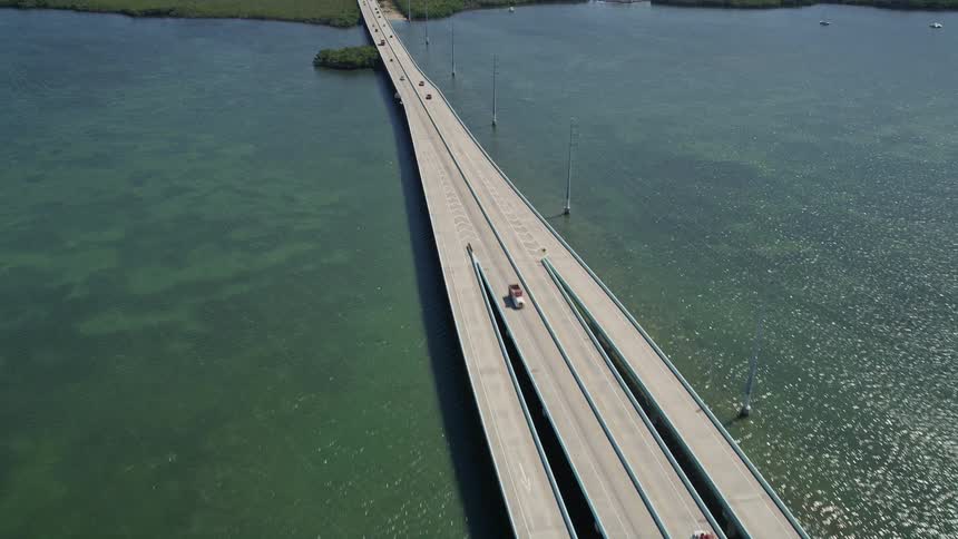 An aerial shot follows the Overseas Highway bridge over Lake Surprise revealing the beautiful Key Largo in Florida with tags including transportation aerial vehicle and spring or summer