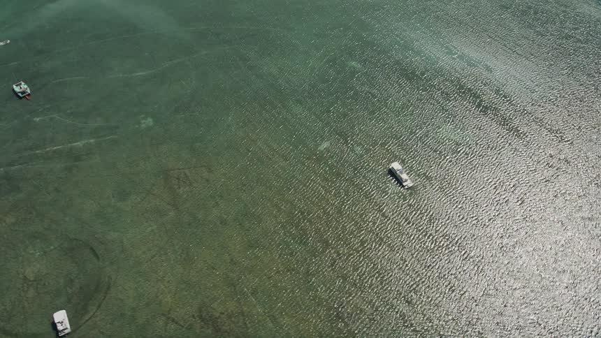Aerial footage of fishing boats and catamarans viewed from a birds eye perspective off the coast of Islamorada Florida during daytime