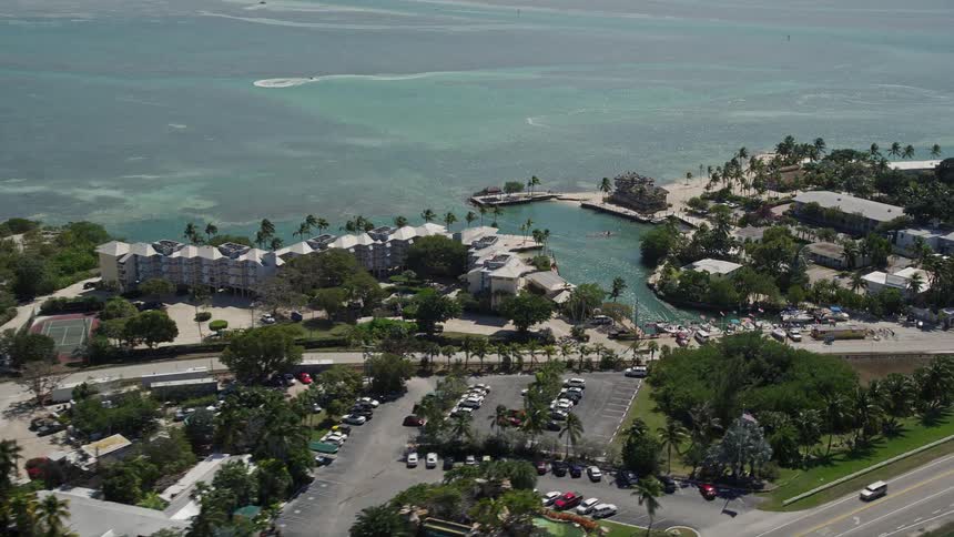 Aerial footage of the Holiday Isle Resort and Marina in Islamorada Florida showcasing the sunny coastline with boats and cars at the popular vacation spot