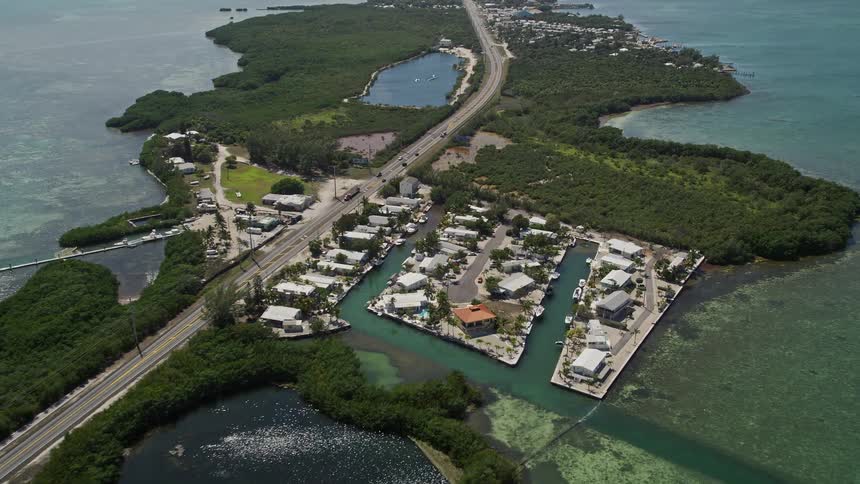 Flying over Grassy Key and along the Overseas Highway with a right pan revealing the coastal landmarks of Marathon Florida