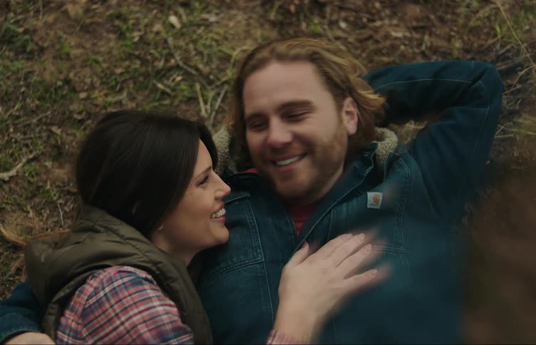 A couple lying together on the ground talks and laughs