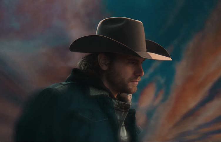 A man wearing a cowboy hat staring forward posing for a photo with a colorful background