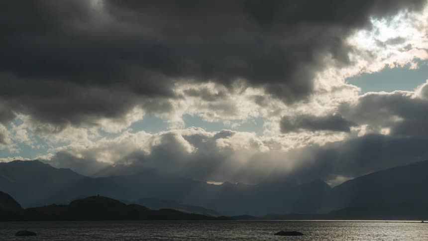 Dense clouds move over the ocean near a mountain