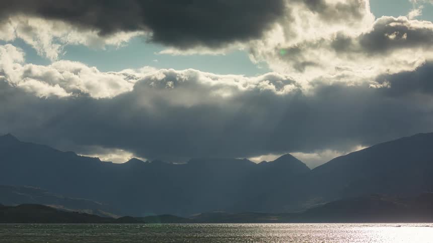 Dense clouds move over the ocean near a mountain range