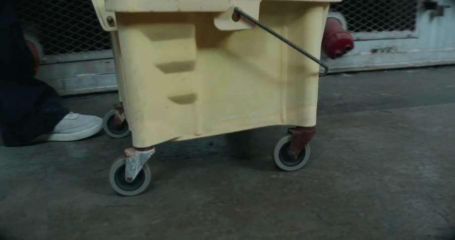 A worker pushes the mop bucket