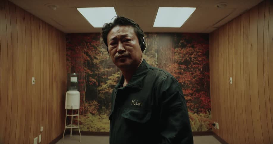 A janitor vacuums a wood paneled room