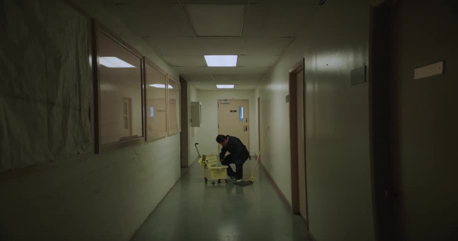 A man is cleaning an empty hallway