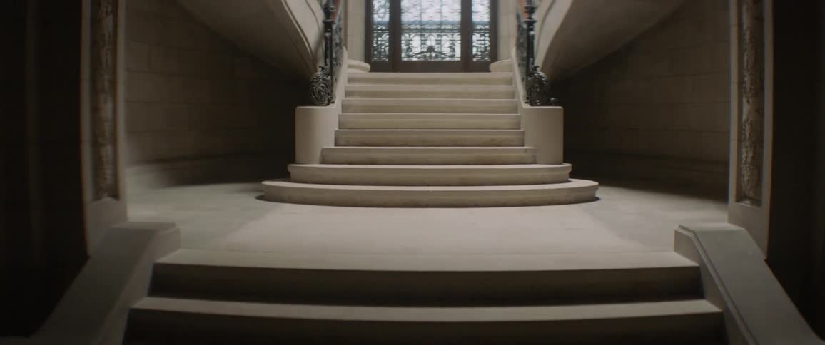 Wide stone steps in a building lead up to a large ornate window