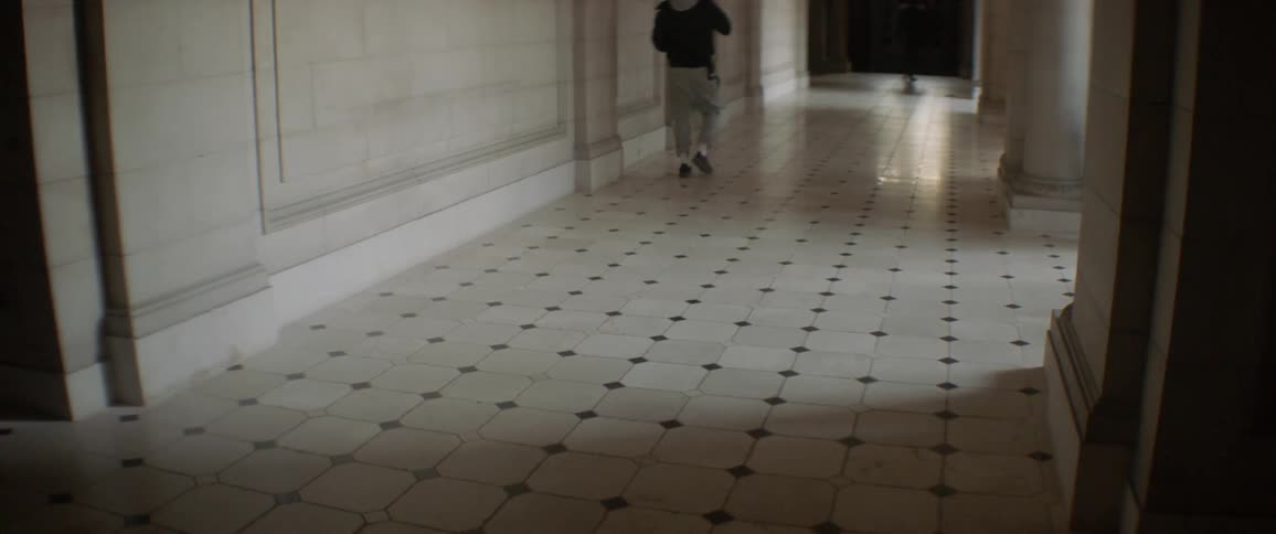 People walk down a tiled hallway
