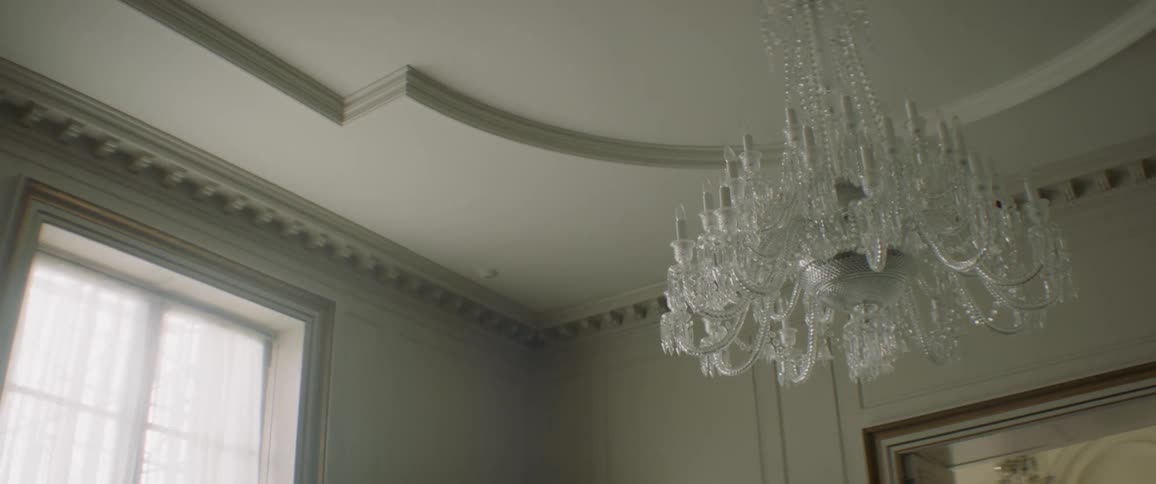 A chandelier is hanging from a ceiling inside in daylight