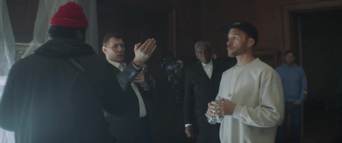 A group of me talk and gesture on a film set