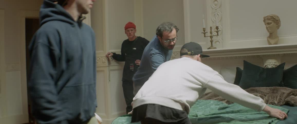 A man prepares making a bed with people watching