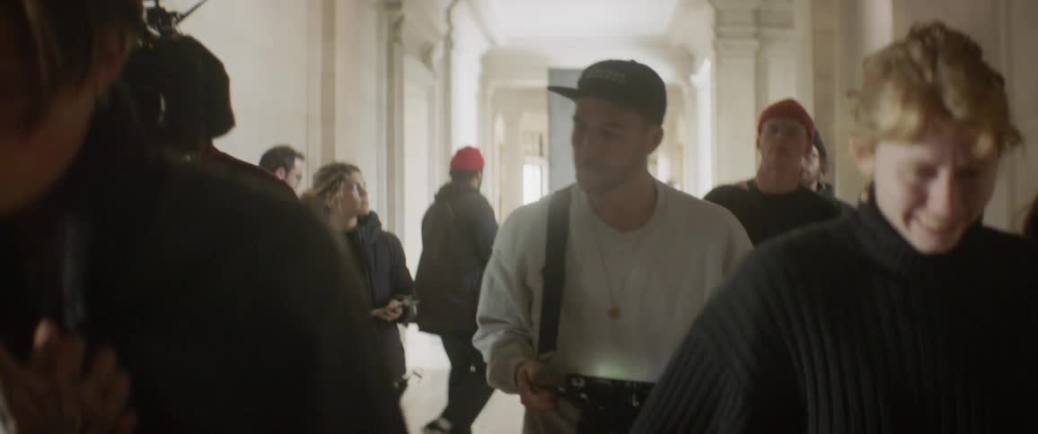 A film crew walks down the hallway together