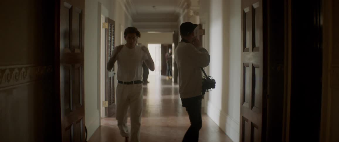 Two men walk down a hallway