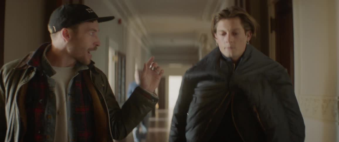 Two people talk as they walk down the hall