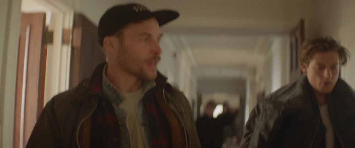 Two men talk as they walk down the hallway
