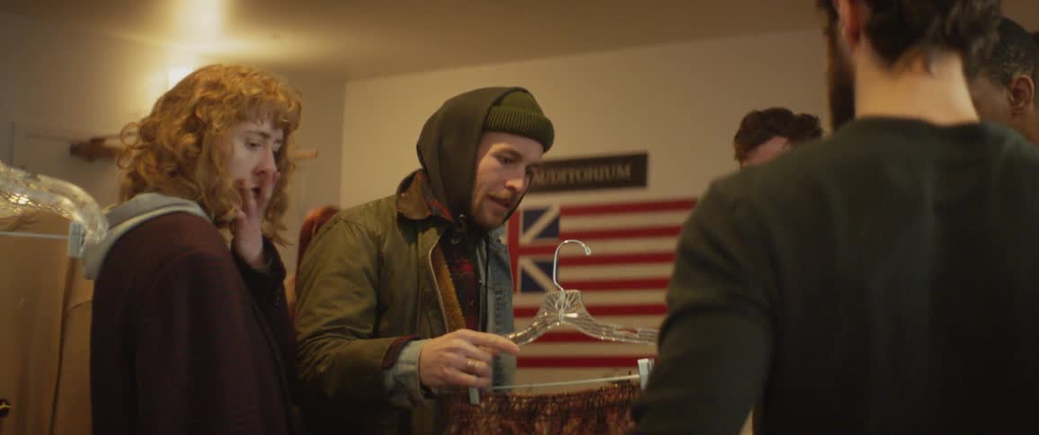 A man hands off some clothes from a wardrobe