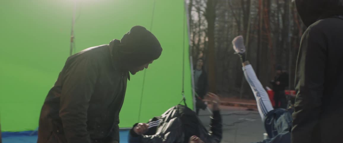 Film crew records a man suspended by wires in front of a green screen