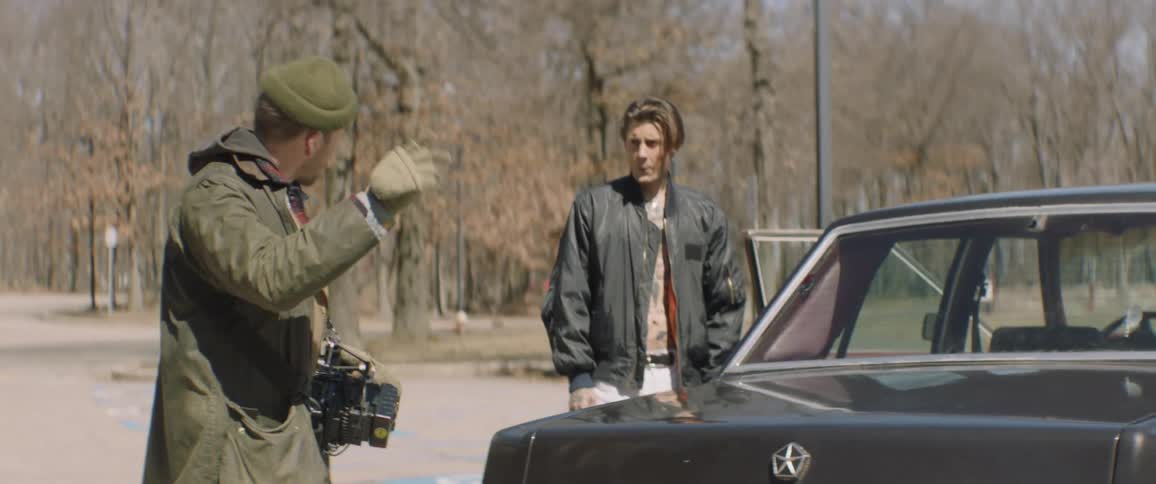 Two people talk near the opened car