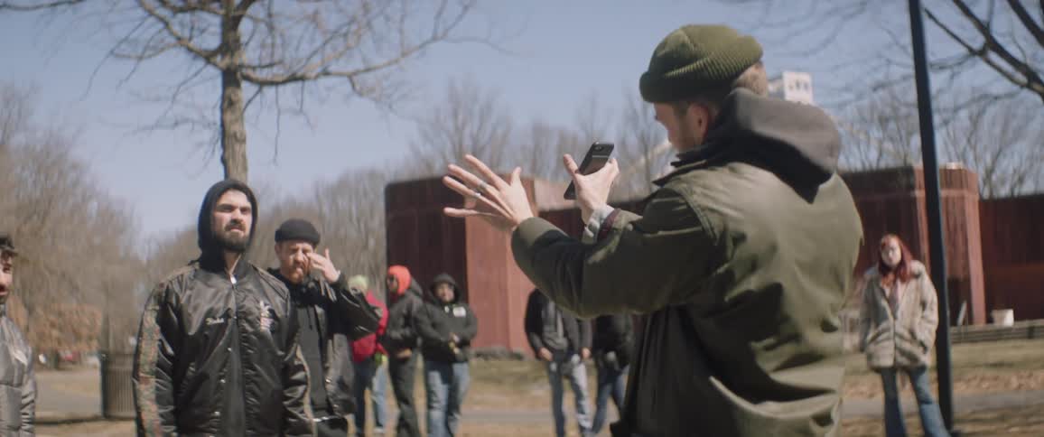 Camera crew films outside a large building near trees