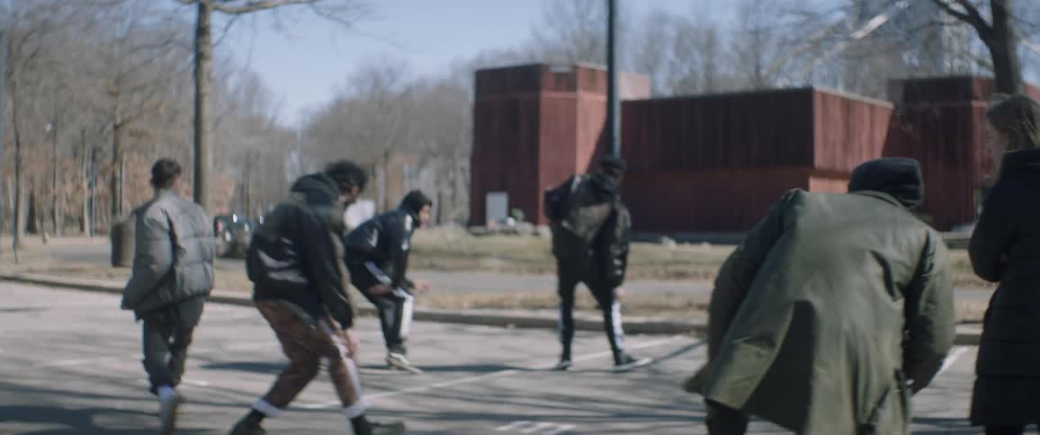 Several people dance in unison in a parking lot