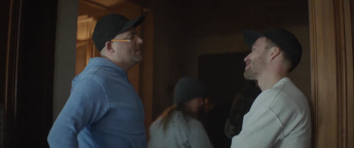 Two men smile and talk in a house