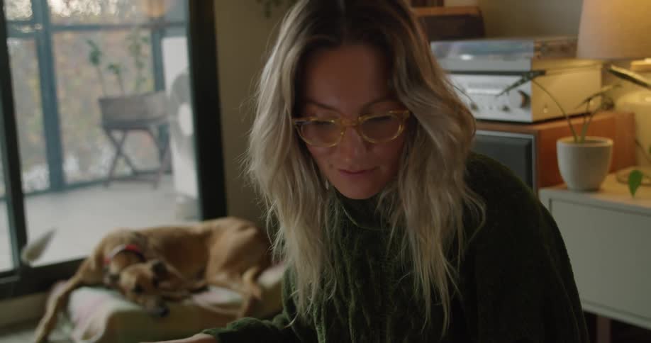 A woman turns away from writing to turn the page in a book
