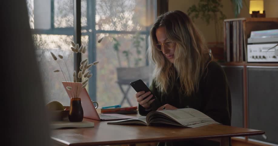 A woman is sitting inside and using her cellphone