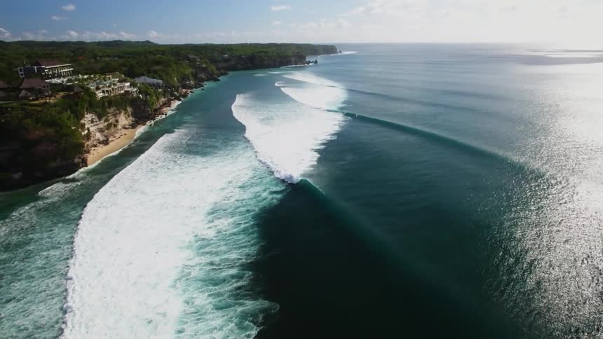 An overhead view of the ocean and the waves come in to hit the beach area