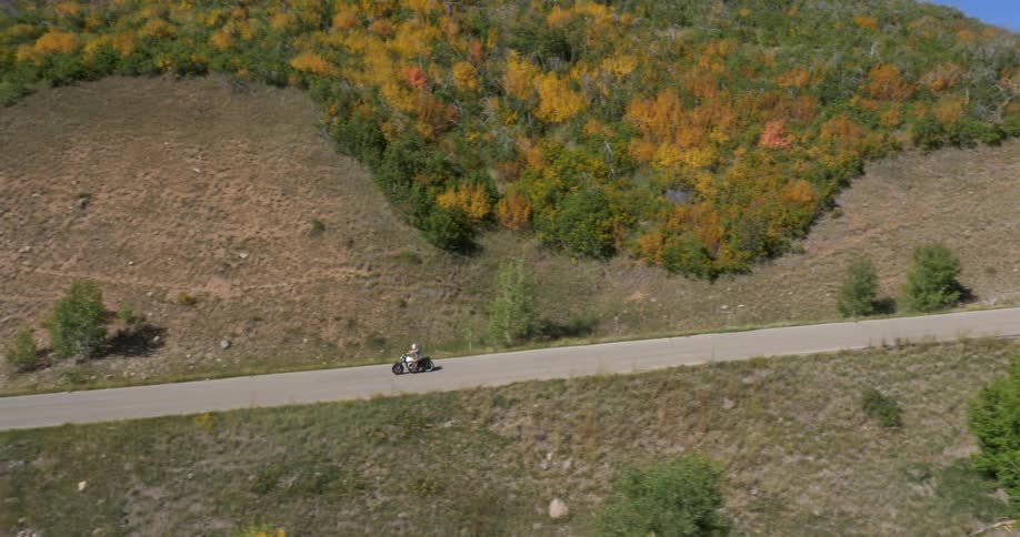 A person on motorcycle races down a small road below