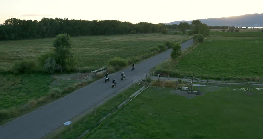 A group of motorcyclists all perform a stunt where they stand on their moving bikes
