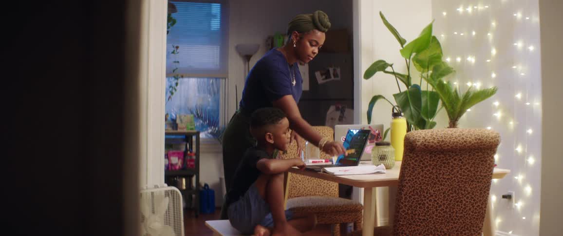 A mother sits down with her son to help with homework