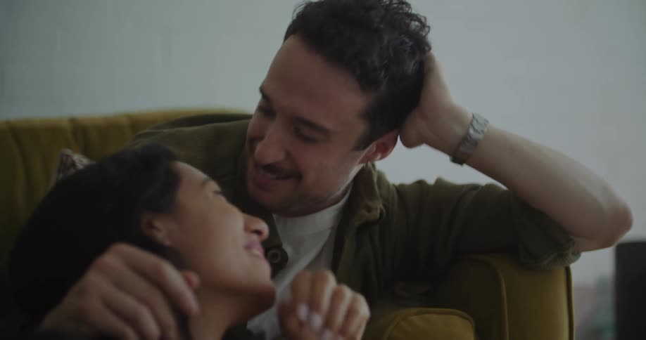 A man and woman looking at a laptop then each other kissing and smiling