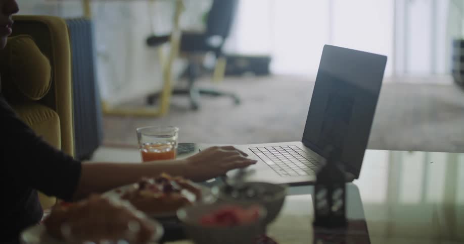 Man viewing smartphone laughs and talks with woman using a laptop in living room