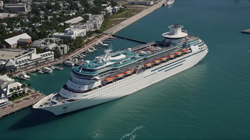 Aerial footage of a Royal Caribbean cruise ship sailing past the coastline of Key West during a sunny day