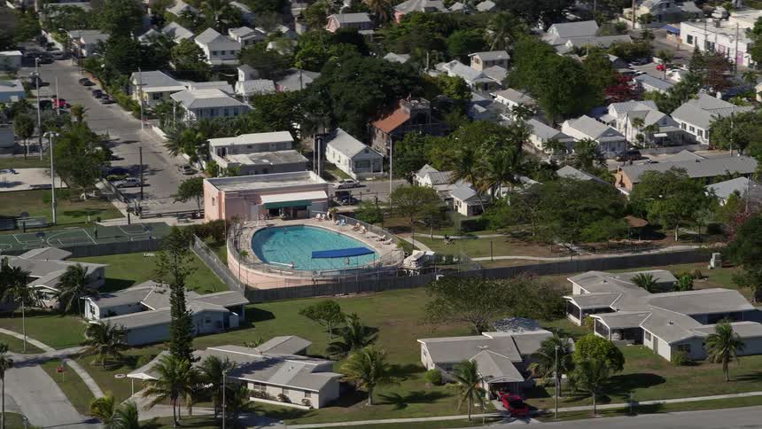 An aerial view of a large pool behind a house in a Key West neighborhood on a sunny day