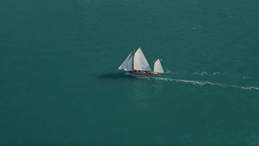 A sailboat gracefully sails on crystal clear waters of Key West Florida in aerial footage