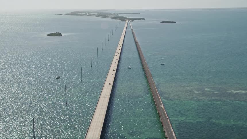 Aerial footage of crossing the Seven Mile Bridge in Florida following light traffic and approaching the island