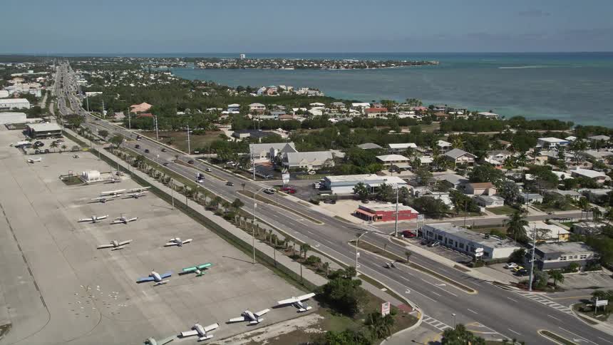 Aerial footage of cars driving on Overseas Highway along the coastline of Marathon Florida during the daytime in summer