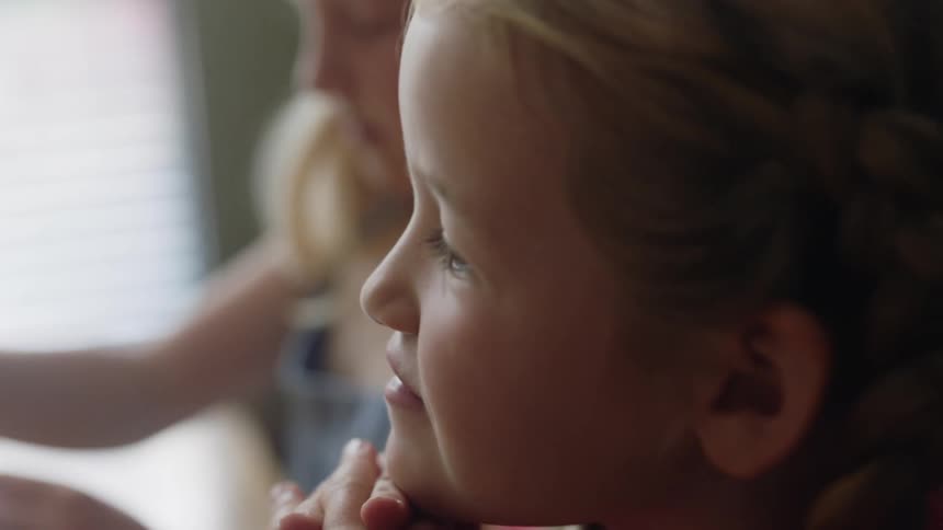 A little girl with braids stares at birthday cake