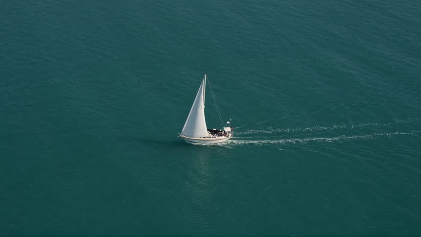 Aerial footage of a sailboat leisurely sailing along the shores of Key West Florida on a sunny summer day