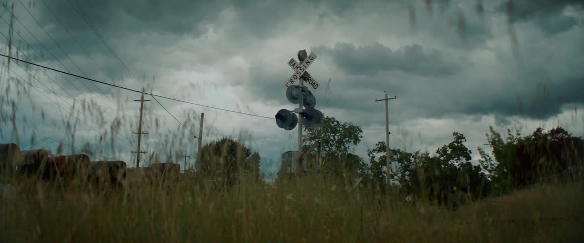 A railroad crossing sign under dark clouds