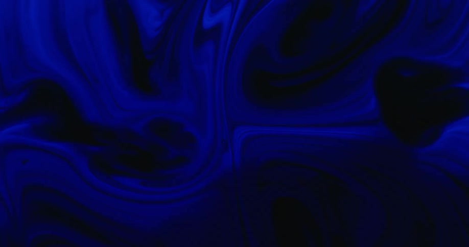 A dark blue liquid swirls and flows as it mixes with a black liquid