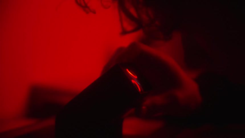 Photographer in dark room using a negative viewfinder to inspect negative film