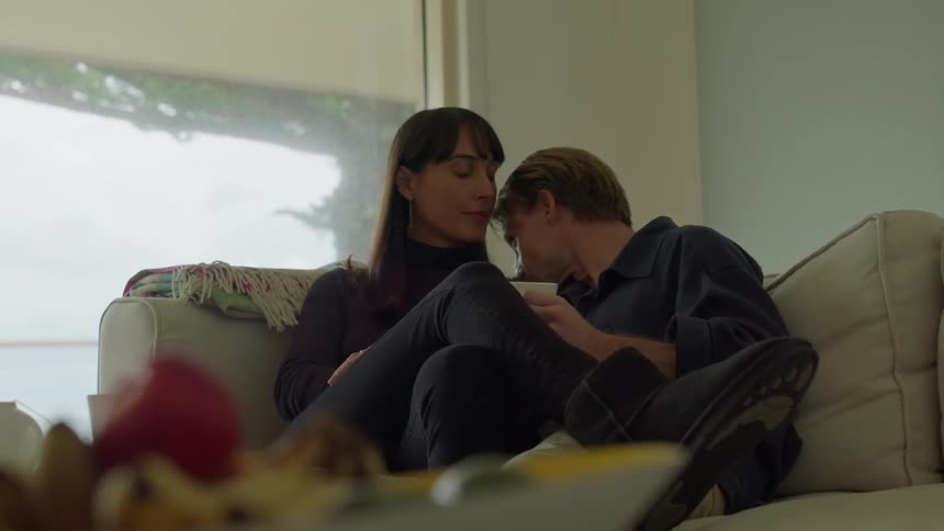 Man and woman sitting on couch together having an intimate conversation puts head on shoulder daytime