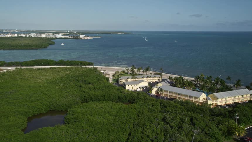 Aerial view of Key West International Airport takeoff and reveal of a resort and hotels along the shoreline in Key West Florida