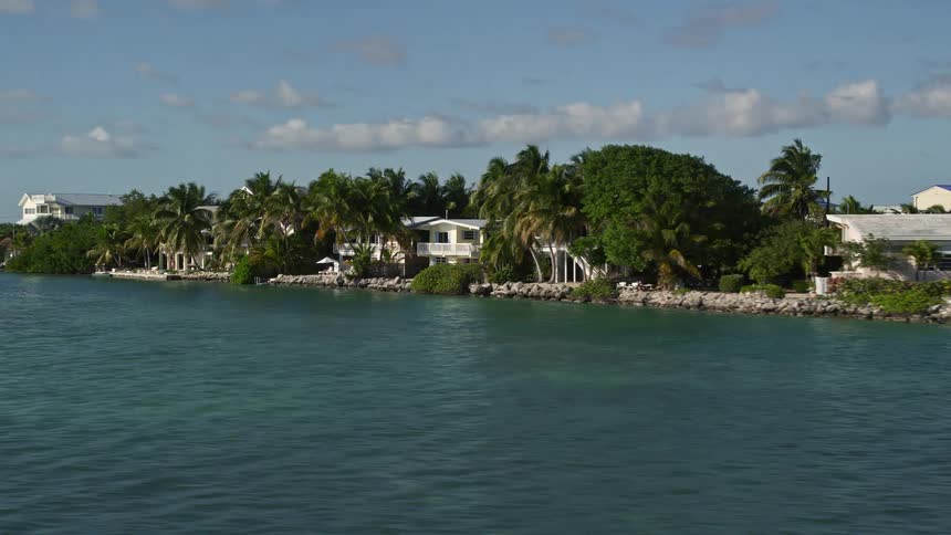 A low-flying aerial view of beach houses and palm trees on a sunny day in the coastal community of Summerland Key in Florida