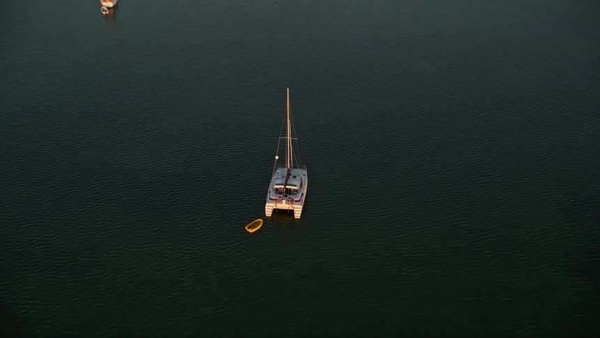 Approaching a catamaran and sailboats at sunset in Key Largo Florida from an aerial 
