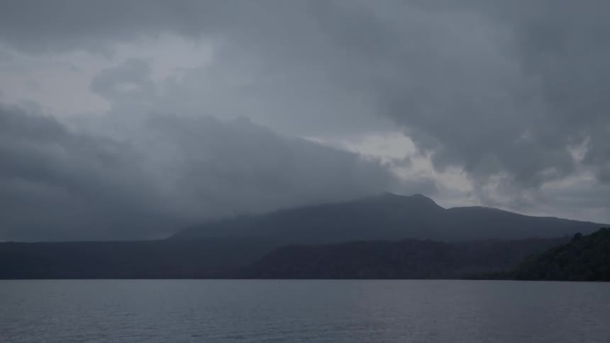 Clouds over a mountain behind a lake