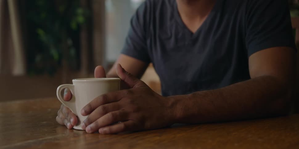 A man is sitting at a table with coffee cup